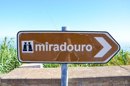Old, partly damaged brown tourist sign saying miradouro in Portuguese. Information signs. Marking system. Arrow with a symbol of binocular. TRANSLATION: miradouro means viewpoint.の写真素材