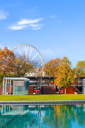 Budapest, Hungary - Nov 6, 2019: Streets of Hungarian capital city with trees in the fall colors. Water from fountain in the foreground. Budapest Eye in the background. Largest European ferris wheel.のeditorial素材