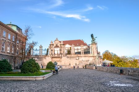 Budapest, Hungary - Nov 6, 2019: Historical courtyard of the Buda Castle. Statue of the mythological bird Turul and historical staircase in the background. Tourist landmark, people on the square.のeditorial素材