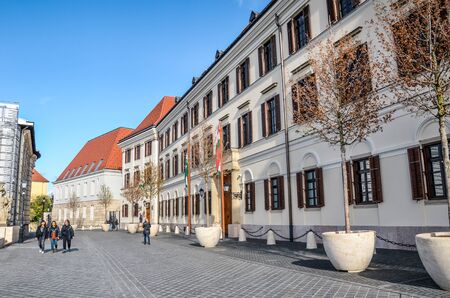Budapest, Hungary - Nov 6, 2019: Cobbled street in the Castle District with the building of the Court Theatre of Buda. Budapest historical center. People walking on the street.のeditorial素材