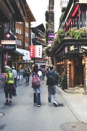 Zermatt, Switzerland - July 10, 2019: Street with tourists in beautiful Alpine village Zermatt in the summer season. The city center with people. Shops, cafes and restaurants.のeditorial素材