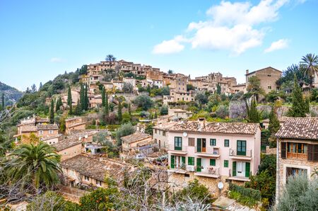 Stunning cityscape of the small coastal village Deia in Mallorca, Spain. Traditional houses located in terraces on the hills surrounded by green trees. Spanish tourist destinations.の写真素材