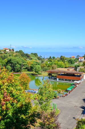 Santana, Madeira, Portugal - Sep 24, 2019: Vertical photo of the Madeira Theme Park. Green trees, lake, houses and walking path. Exhibition centre dedicated to the Portuguese islands.のeditorial素材