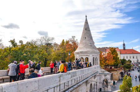Budapest, Hungary - Nov 6, 2019: Tourists sightseeing and taking photos of Fishermans Bastion in the Hungarian capital city. Built in Neo-Romanesque style. Trees in autumn colors in the background.のeditorial素材