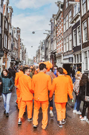 Amsterdam, Netherlands - April 27, 2019: Young people dressed in national orange color while celebrating the Kings day, Koningsdag, birthday of the Dutch King Willem-Alexander. Street celebration.のeditorial素材