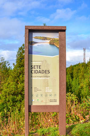 Sete Cidades, Azores, Portugal - Jan 12, 2020: Information sign for tourists in Sete Cidades. Wooden tourist sign in Portuguese Protected Landscape Area. Green forest in background. Vertical photo.のeditorial素材