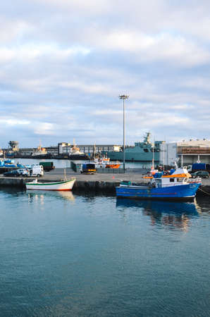 Ponta Delgada, Azores, Portugal - Jan 12, 2020: Industrial harbor in the capital city of Portuguese Azores Islands. Boats and cargo ships moored in the harbour by the Atlantic ocean. Vertical photo.のeditorial素材