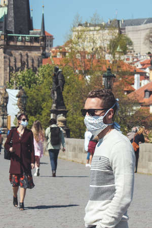 Prague, Czech Republic - April 23, 2020: People wearing medical face masks on the Charles Bridge. Old town in background. City center during coronavirus pandemic. COVID-19 crisis. Selective focus.のeditorial素材