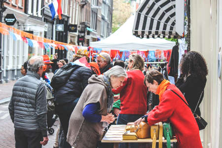 Amsterdam, Netherlands - April 27, 2019: People buying and selling on the traditional flea market during the Kings day, Koningsdag. Streets decorated with Dutch flags and national colors.のeditorial素材