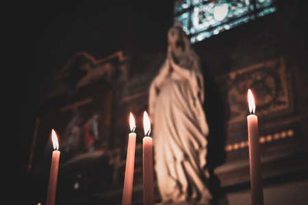 Candles lit in the church with the altar and christian icons in the background. Roman Catholic religion. Religious conceptの写真素材