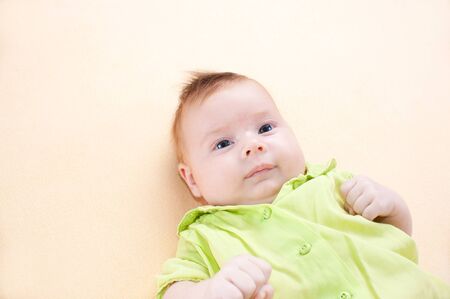 Newborn baby in green chemise  on yellow background