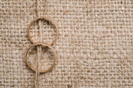 Two gold wedding rings lying on brown cloth sackingの写真素材
