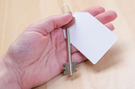 white paper tag attached to the metal silver key in handの写真素材