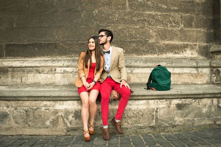 Young couple sitting on an old stone wall, green backpackの写真素材