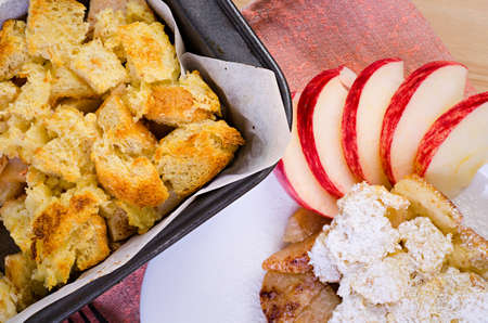 apple pie on a white plate decorated with raw apples on a wooden backgroundの写真素材
