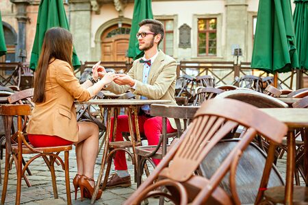 Young fashion elegant stylish couple posing on cafe of european city in summerの写真素材