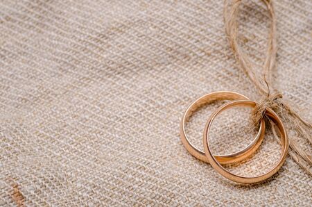 Two gold wedding rings lying on brown cloth sackingの写真素材