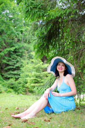 Beautiful young girl sitting on the green grass in the meadowの写真素材