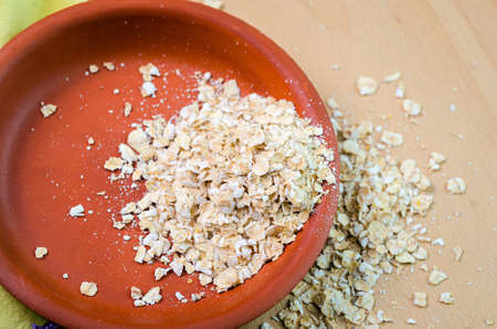raw oatmeal in a bowl on wood board