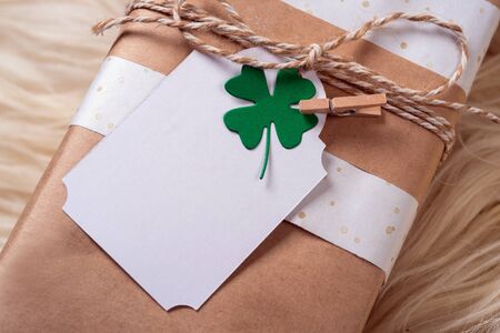 brown gift craft box with empty message cart with green shamrock clover leaf on wood backgroundの写真素材