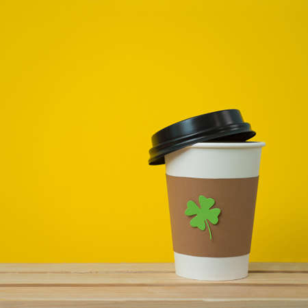take away cup with cut and pasted green shamrock symbol on wood board  on orange backgroundの写真素材