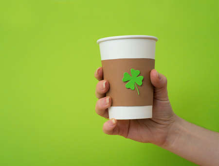 take away cup in a hand with cut and pasted green shamrock symbol on green backgroundの写真素材