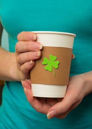 take away cup in a hand with cut and pasted green shamrock symbolの写真素材