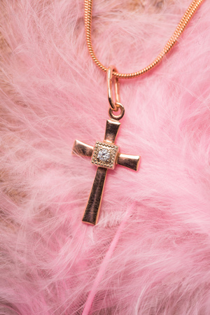 golden cross on a chain on a pink backgroundの写真素材