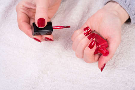 manicured woman's nails with red nail polish on white towelの写真素材