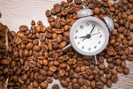 vintage alarm clock and coffee beans on wooden table