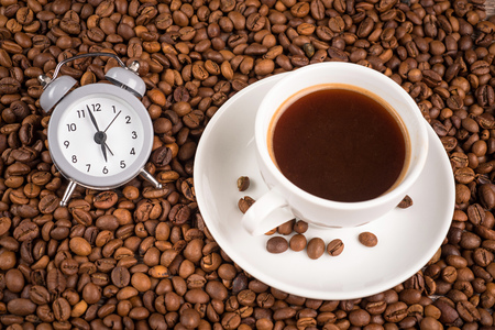 Cup of coffee, clock and coffee beans on a table