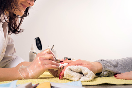 Closeup shot of a woman in a nail salon receiving a manicure by a beautician with nail file. Woman getting nail manicure.の写真素材