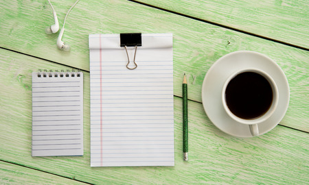 Open notebook with cup of coffee on green wooden desk