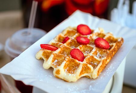 a Belgium waffles with strawberries on paper plateの写真素材