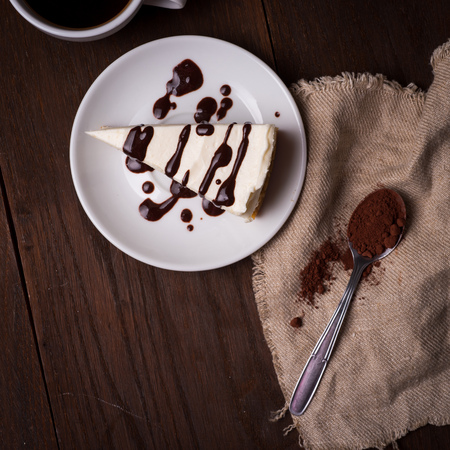slice of cheesecake with coffee on dark background. cup of coffee and a dessert on plateの写真素材