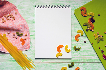 White notebook with spices and noodles on green wooden background. kitchen conceptsの写真素材