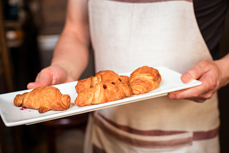 baker concept. baker concept. Fresh croissants on white plate on wooden backgroundの写真素材