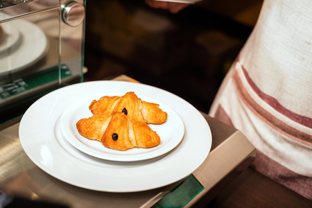 baker concept. Fresh croissants on white plate on wooden backgroundの写真素材