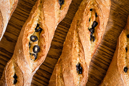 baker concept. closeup of some baguettes or bread rolls on a wooden table in bakery. Fresh baguettes with oliveの写真素材
