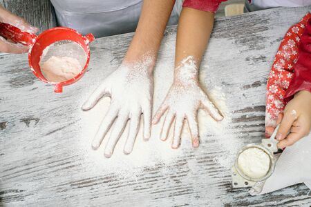 Happy family preparation holiday food. Family cooking Christmas cookies. Hapiness and people concept. Kids making dough in white kitchen. Happy family in making cookies at home.の写真素材