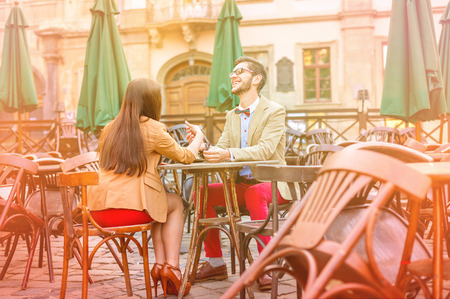 Young fashion elegant stylish couple posing on cafe of european city in summerの写真素材