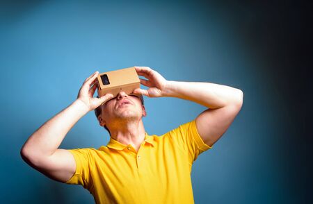 Concept of virtual reality carton glasses and interfaces. young man in yellow t-shirt enjoying vr glasses.の写真素材