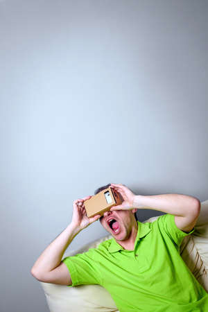 Concept of virtual reality carton glasses and interfaces. young man in green t-shirt man enjoying vr glasses.の写真素材