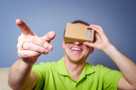 Concept of virtual reality carton glasses and interfaces. young man in green t-shirt man enjoying vr glasses.の写真素材