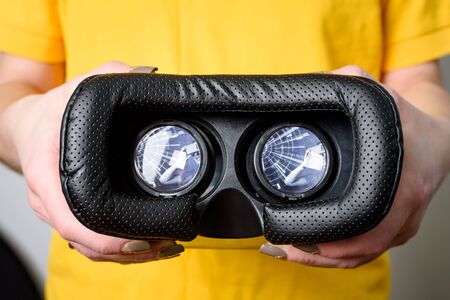 Virtual reality concept. Man or women holding in Hand VR glasses device with futuristic image in lensの写真素材