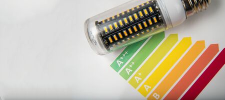 Energy efficiency concept with energy rating chart and LED lamp on white backgroundの写真素材