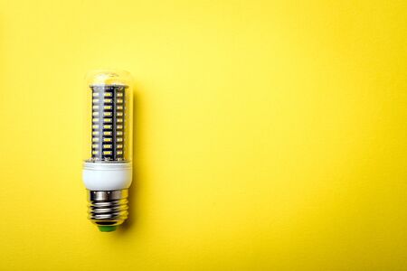 Energy saving LED light bulb on a yellow background with empty spaceの写真素材