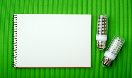 Energy saving LED light bulb with empty notepad on a green backgroundの写真素材