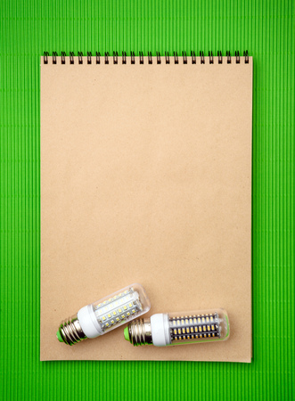 Energy saving LED light bulb with empty notepad on a green backgroundの写真素材
