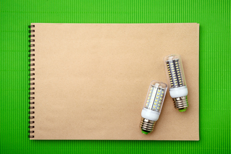 Energy saving LED light bulb with empty notepad on a green backgroundの写真素材